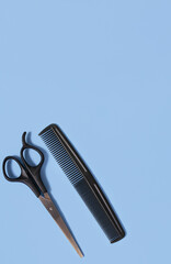 Hairdressing scissors and a comb on a blue background. The concept of a hairdresser, beauty salon, tools. Copy space. View from above.