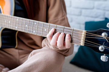 Fototapeta na wymiar Closeup of woman playing guitar at home