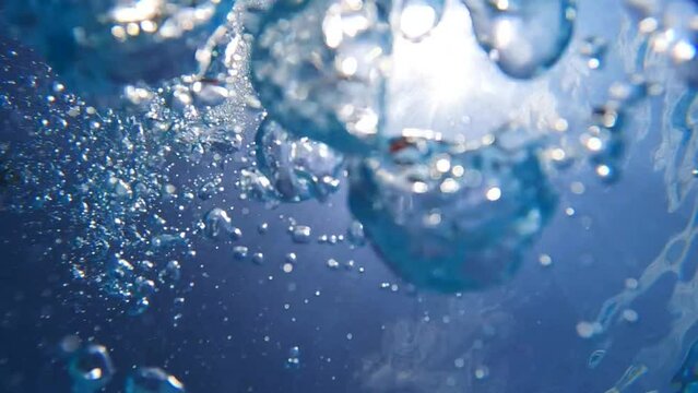 Underwater slow motion loop video of diver releasing air bubbles flowing towards sea surface in tropical exotic bay with deep blue waters
