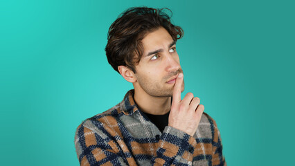 Obraz premium young handsome turkish man thinking and looking up blue background