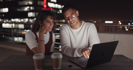 Laptop, collaboration and night with a business team working together on balcony in the city. Teamwork, computer and overtime with a man and woman employee at work late on a project deadline