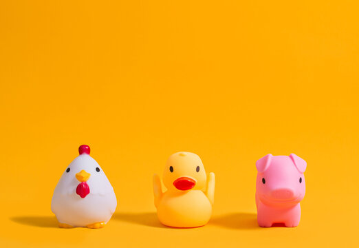 Rubber duck, pig and rooster for bathing on a yellow background. Children's toys. Copy space.