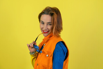 Young woman with glasses on a yellow background.Charming smiling woman poses against yellow studio wall.