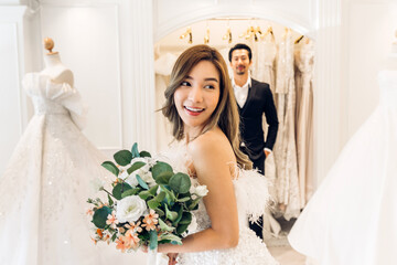 Portrait of smiling cheerful happy love asian couple fashion bride man and woman posing in white wedding dress for pre wedding hug together at wedding interior fashion studio