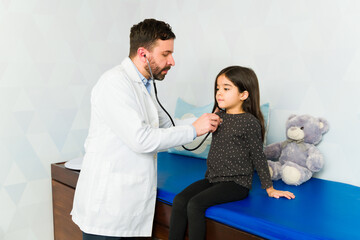 Pediatrician checking the heartbeat or breathing of a kid patient