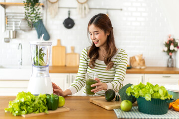 Portrait of beauty healthy asian woman making green vegetables detox cleanse and green fruit smoothie with blender.young girl drinking glass of green fruit smoothie in kitchen.Diet concept.healthy 