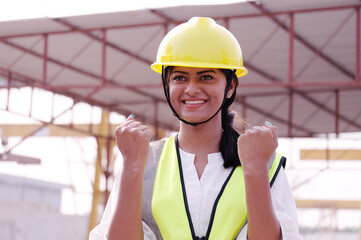 Female worker wearing a safety helmet smiling thumbs up.