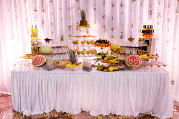 Beautiful festive candy bar with a lot of berries, chopped fruits platters and alcohol drinks....