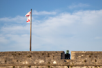 cannon and flag on the top of a fort stone wall