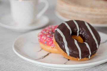 Delicious dessert. Pink and chocolate donut, with multicolored sprinkles, a cup of black coffee or tea. Sweets.
