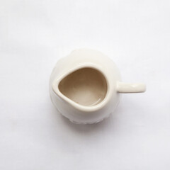 Empty ceramic creamer isolated on white. Top view of a tiny pitcher to serve cream or sauce
