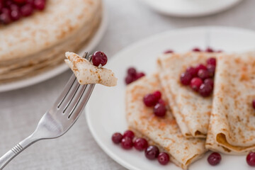 Russian traditions. Russian holiday Maslenitsa. Still life with a cup of tea, a stack of pancakes with northern cranberries, cubes of butter on the table.