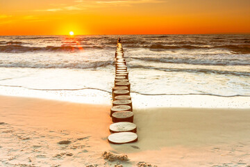 Sunset on the Baltic Sea in Rowy, Poland. Landscape with waterbreak in the sea under the sky at...