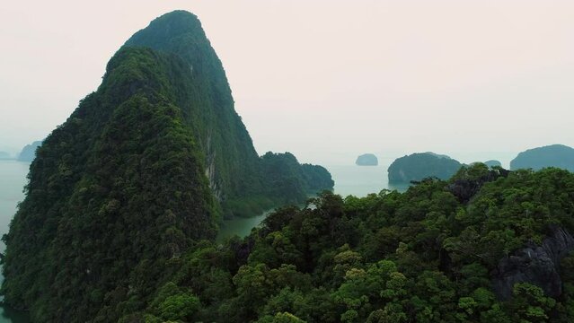 Phang Nga Bay. Rocky islands in the sea with steep slopes overgrown with green trees in the sea bay, the coast is densely overgrown with trees. Top view from a drone. Beauty of marine tropical islands