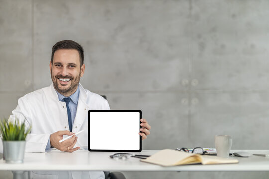 Portrait of male doctor holding digital tablet and looking at camera