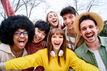 Multiracial group of happy friends taking a mobile selfie in urban park. Positive international...