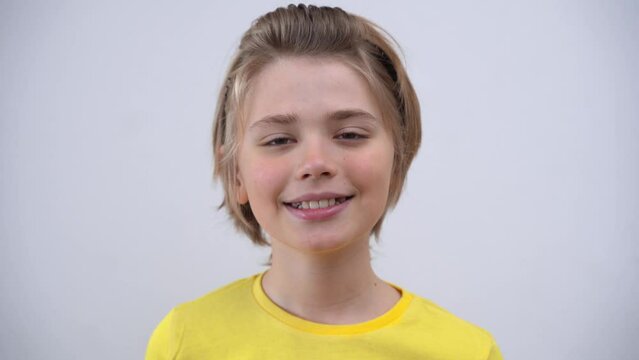 Close-Up Of Smiling Handsome SchoolBoy Long Hair in Yellow T-Shirt Looking At Camera Over white Background. Positive Teen Mood. Advertising Copy Space