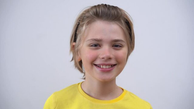 Close-Up Of Smiling Handsome  SchoolBoy Long Hair in Yellow T-Shirt Looking At Camera Over white Background. Positive Teen Mood. Advertising Copy Space