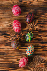Colorful Easter eggs on brown wooden background. Traditional Ukrainian pysanka handmade technique. DIY festive symbols. Spring holiday decoration background.