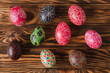 Colorful Easter eggs on brown wooden background. Traditional Ukrainian pysanka handmade technique. DIY festive symbols. Spring holiday decoration background.