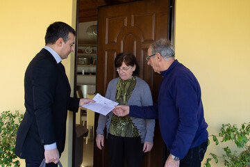 Image of a sales rep and door-to-door salesman explaining his products for sale to an older couple. Harassing seller and scammer.
