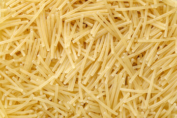 Pasta raw, vermicelli, background uniform texture, small cylinders in bulk close-up, top view