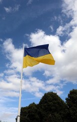 yellow and blue flag of Ukraine and sky with clouds in background