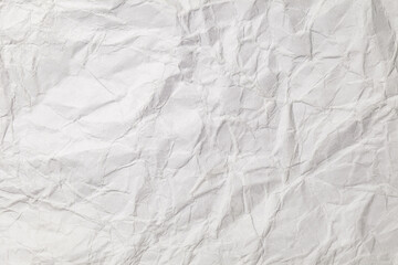 Crumpled white paper with bends and fractures, uneven surface, background texture, close-up