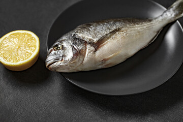 Dorado, raw fresh uncooked fish source of omega 3, yellow lemon, on dark background, side view, selective focus