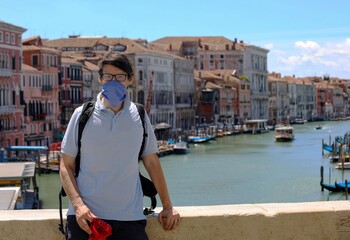 man tourist in venice in ITALY with face mask on the Rialto Bridge