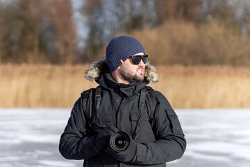 Male photographer in winter clothes and sunglasses in winter outdoors.