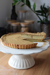 Isolate pumpkin pie on a plate, holding a cut slice. Served on a wooden table