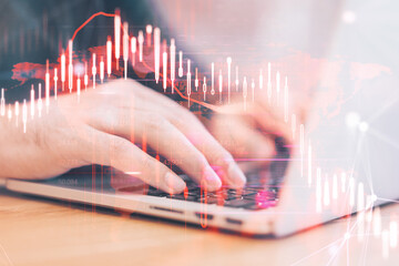 Close up of hands using laptop computer with glowing falling red forex chart on blurry background. Stock exchange and crisis concept. Double exposure.