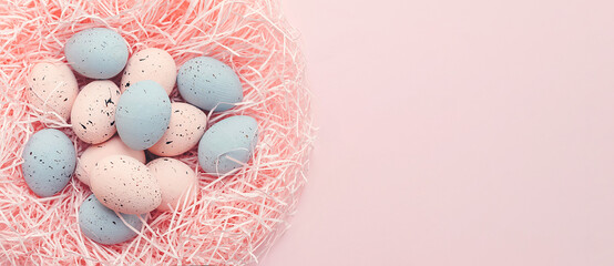 Banner. Easter eggs, feathers in a nest on pink background. The minimal concept. Top view. Card...