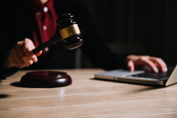 Justice and law concept.Male judge in a courtroom with the gavel, working with, computer and docking keyboard, eyeglasses, on table in morning light