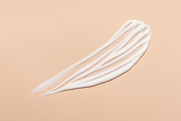 White cream swatch on nude beige background. Creamy skincare texture. Beauty product spot sample