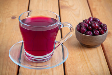 A glass of rose hip tea and rosehip seeds on wooden table