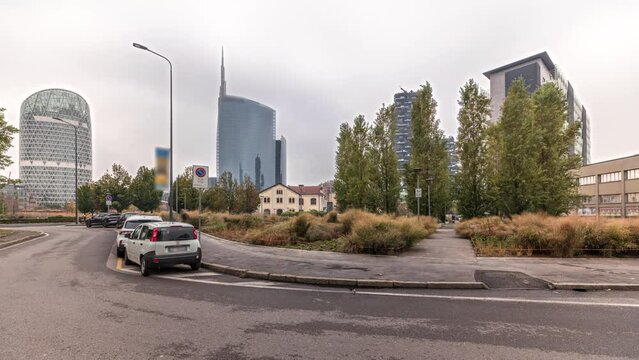 Panorama showing skyscrapers and towers from park with outumn treea and green lawn timelapse. Located between Piazza Gae Aulenti and the Isola district. Traffic on a road. Milan. Italy