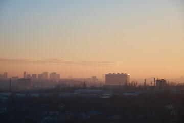 city at sunset, panorama of city, outlines of buildings, smog over industrial zone