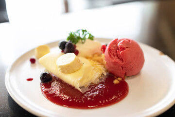 Soft crape with sorbet ice cream with berry juicy sauce and banana sliced with crumble.