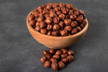 View of a bowl full of hazelnuts on a dark background
