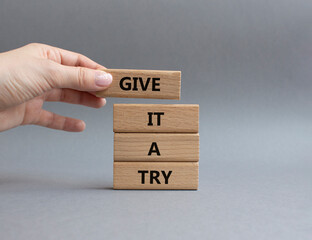 Give it a try symbol. Concept words Give it a try on wooden blocks. Beautiful grey background. Businessman hand. Business and Give it a try concept. Copy space.