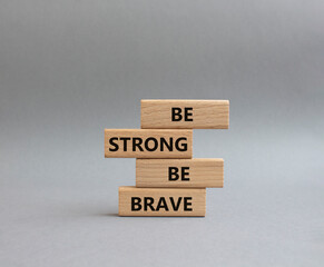 Be strong be brave symbol. Concept words Be strong be brave on wooden blocks. Beautiful grey background. Business concept. Copy space.