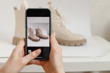 Woman takes a Picture of New or use Shoes on a Mobile Phone at Home. Mobile shooting goods for sale