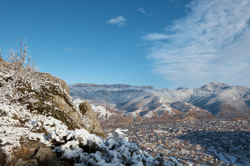 winter, view from mountain to small town, snow rocks and stones, village in distance