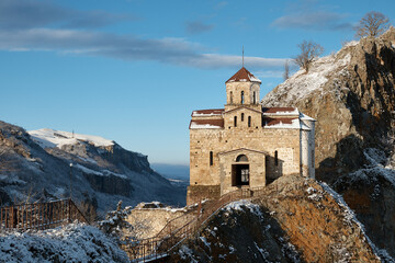 Fototapeta premium church on rock in snow, monastery on mountain, chapel, pagoda, winter landscape, snow on roof and slopes of mountains, church on rock
