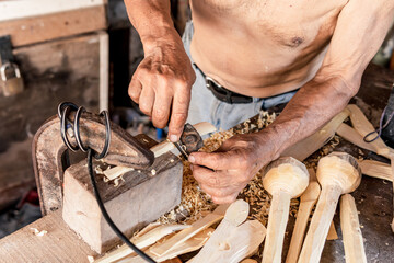 old man carving wooden spoons in the workshop