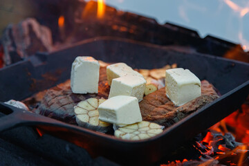 Steak on fire. Cast iron frying pan. Fresh meat. Open fire. Barbecue. Firewood.