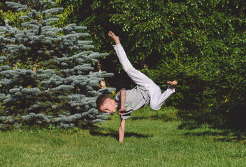 Young caucasian boy playing Capoeira outdoors. Kid exercises acrobatic capoeira figures.