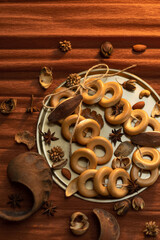  A bunch of bagels lie on a bronze platter, decorated with dried flowers and herbs. On a background of brown corrugated paper